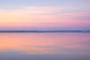 very calm still waters and pink pastel sunset colours reflected in the still lagoon